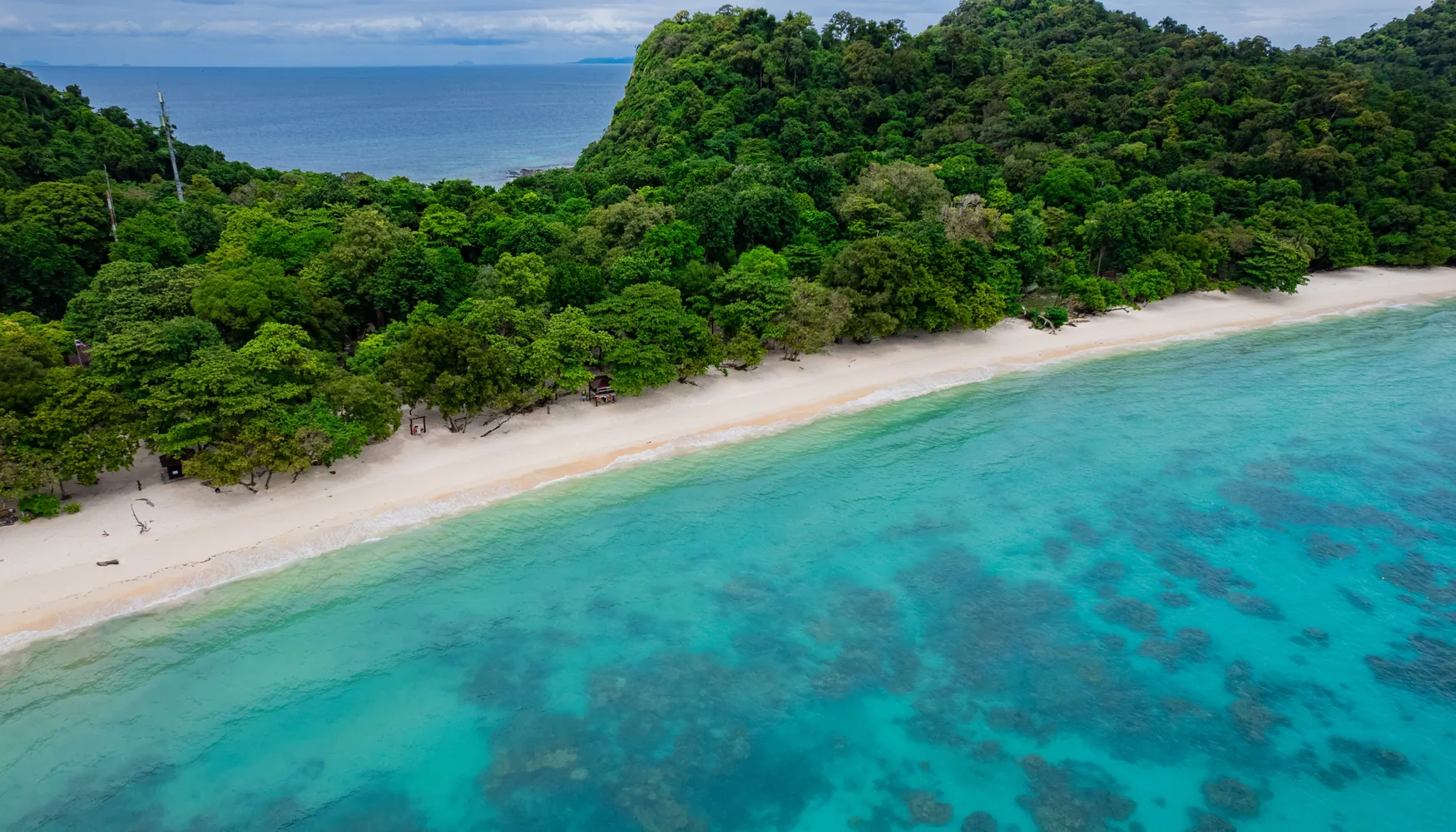 Aerial view of Rok Island's forest and turquoise shoreline