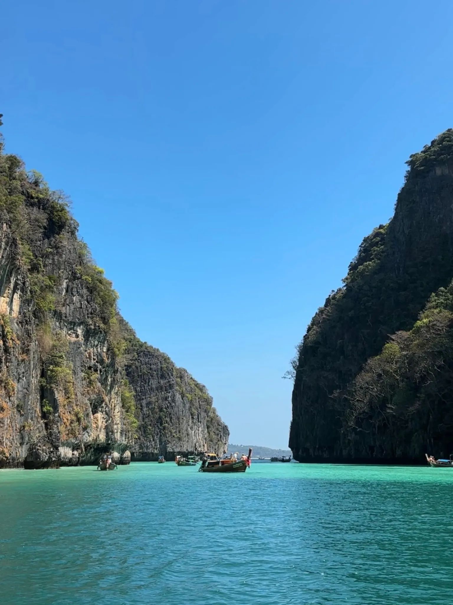Longtail boats floating in the emerald water of Pileh Lagoon
