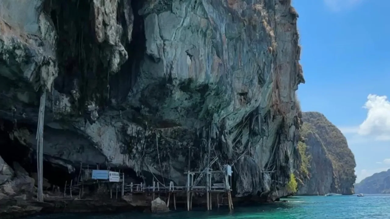 Traditional longtail boat passing Viking Cave at Phi Phi